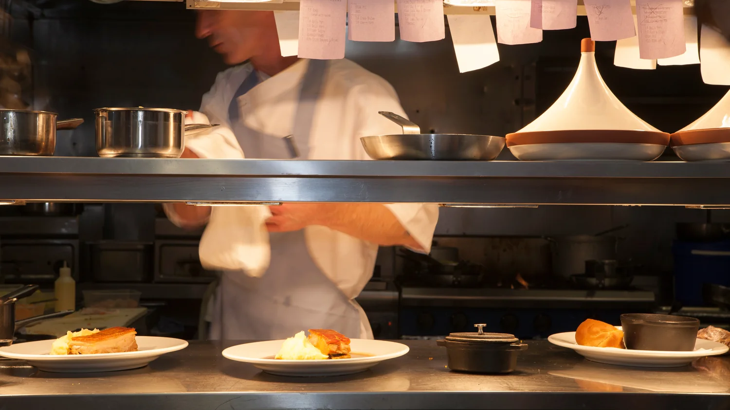 A cook at the pass under a rail of order tickets
