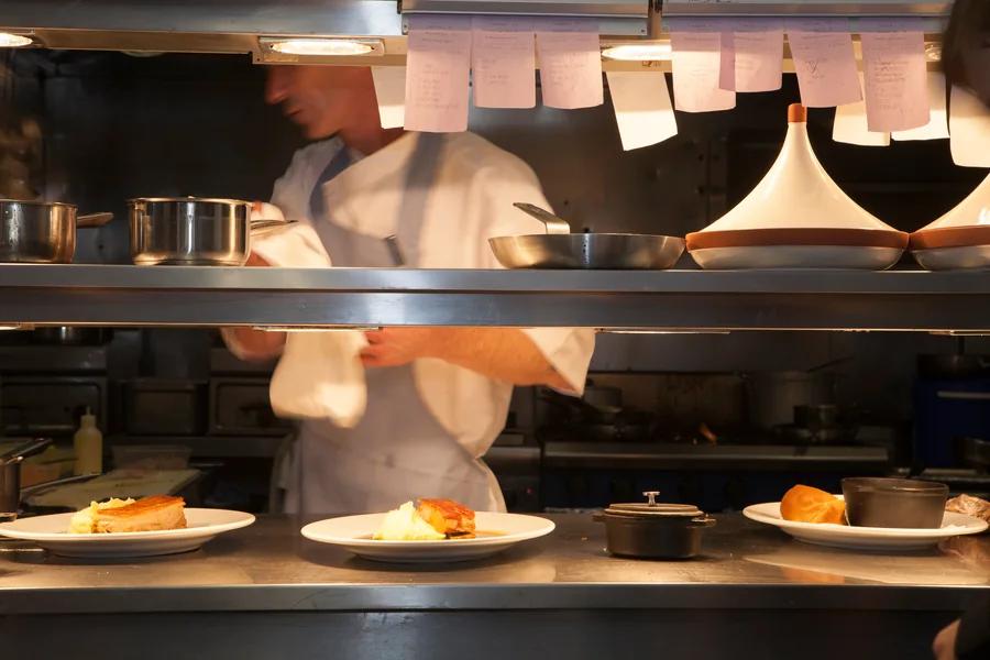 A cook at the pass under a rail of order tickets