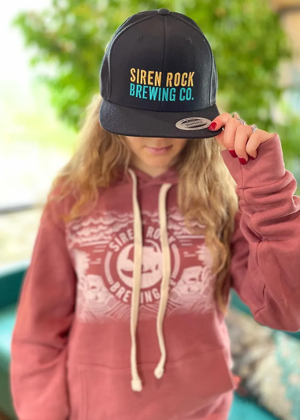 A brewery brand worn out of town on a cap and hoodie