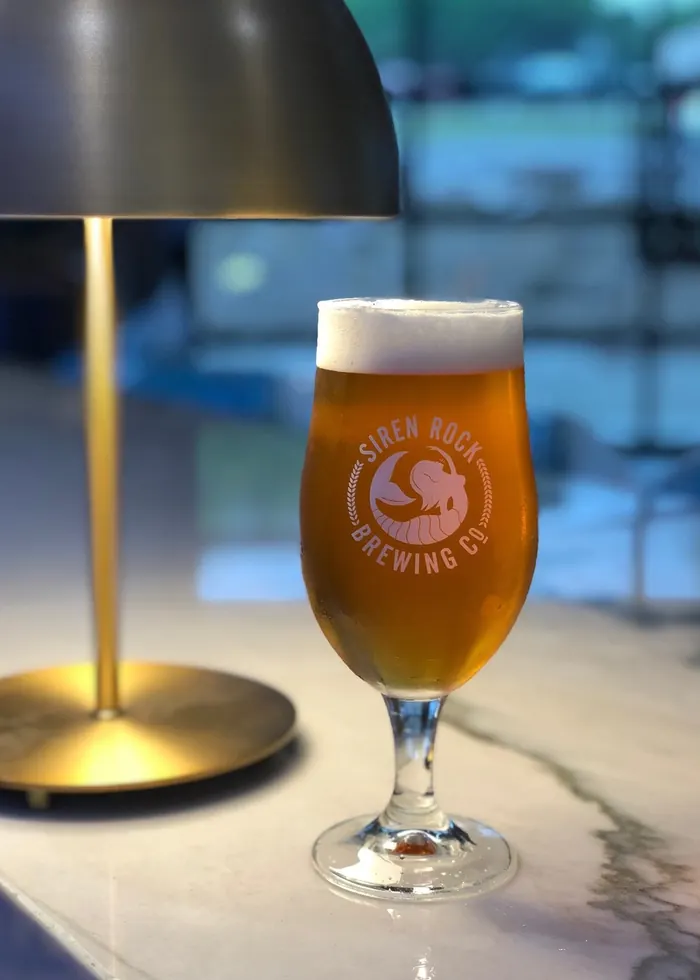 A brass table lamp lighting a glass on a bar top