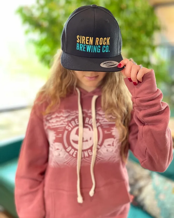 A Siren Rock Brewing Co. embroidered cap and screen-printed hoodie worn together.